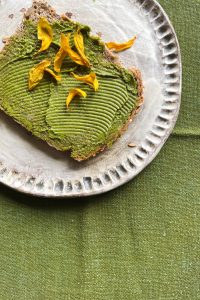 Eine Scheibe Brot mit Matcha-Butter und getrockneten Sonnenblumen-Blättern